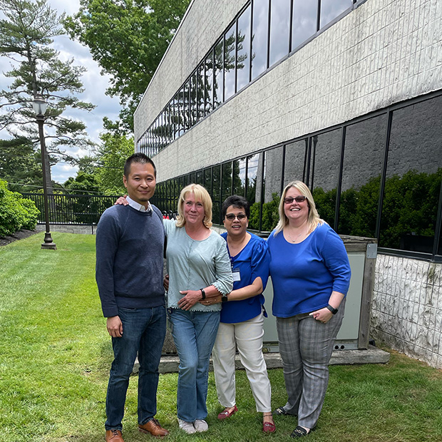 A group of four Kimco associates standing together on a green lawn outside our Corporate headquarters.