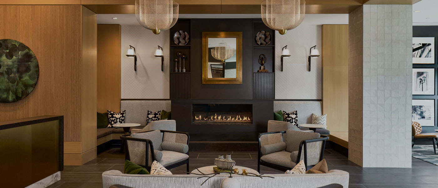 Modern luxury lobby lounge featuring a linear fireplace, contemporary armchairs, and warm decorative lighting.